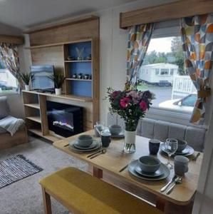 een woonkamer met een tafel en een open haard bij Emi's Caravan in Port Seton