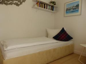 1 cama con sábanas blancas y estante para libros en Haus Uthlande Uthlande Whg 3 Strandliebe, en Wyk auf Föhr