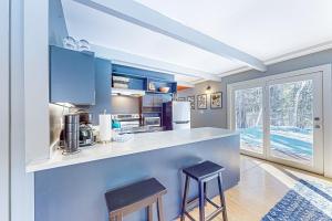 a kitchen with blue cabinets and a counter with two stools at Sugarbush Ski Getaway - Lower in Warren