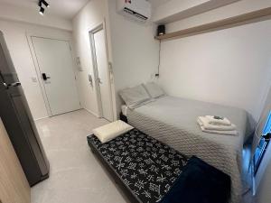 um pequeno quarto com uma cama com um cobertor preto e branco em Studio Jardins Pamplona Cd 1310 em São Paulo