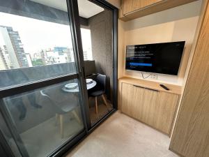 um pequeno quarto com uma televisão e uma janela em Studio Jardins Pamplona Cd 1310 em São Paulo