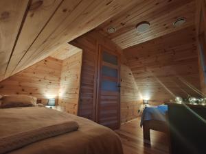 ein Schlafzimmer mit Holzwänden und ein Bett in einem Zimmer in der Unterkunft BAJKA-Domek na wsi in Domaszków