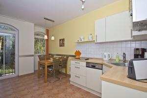 una cucina con mobili bianchi e tavolo di strandnah, gratis Nutzung vom AHOI Erlebnisbad und Sauna in Sellin - Kurparkresidenz FeWo10 a Baabe