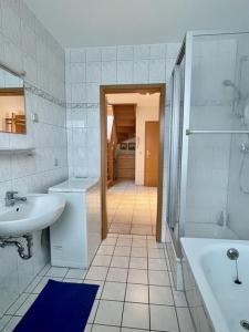 y baño blanco con bañera, lavamanos y bañera. en Birkenstr_ 6 Wohnung 6, en Zingst