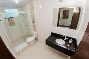 uma casa de banho com um lavatório, um chuveiro e um WC. em Pousada Dom Marujo em Penha