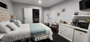 a bedroom with a bed and a desk and a kitchen at Sunkist B & B in Papamoa