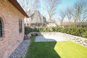 einen Hinterhof mit einem Backsteinhaus und einer Steinmauer in der Unterkunft Ferienwohnung Käthe in Wenningstedt-Braderup