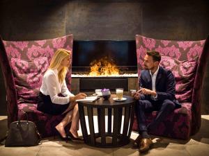 a man and woman sitting around a table in front of a fireplace at Pullman Munich in Munich