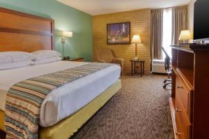 a hotel room with a large bed and a chair at Drury Inn & Suites Atlanta Morrow in Morrow