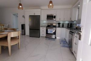 a kitchen with white cabinets and a table and a table and a kitchen with at Villa Cancu, 2 bd, 2.5 bath, wi-fi, pool, Parking in Cabarete