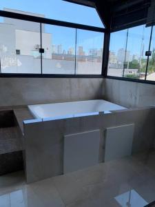 eine große weiße Badewanne in einem Zimmer mit Fenstern in der Unterkunft Loft com Hidro no centro in Balneário Camboriú
