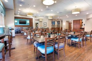 Drury Inn & Suites Burlington في برلنغتون: غرفة طعام مع طاولات وكراسي خشبية