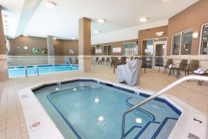 Drury Inn & Suites Burlington في برلنغتون: مسبح في غرفة الفندق مع الكراسي والطاولات