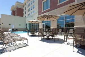 un patio al aire libre con mesas, sillas y sombrillas en Drury Inn & Suites Burlington, en Burlington