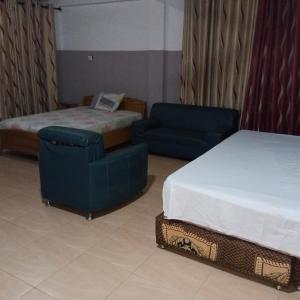 a hotel room with a bed and a bed and a chair at Pemicsa Hotel Accra in Spintex