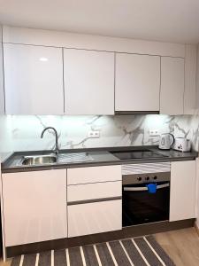 una cocina con armarios blancos y fregadero en Apartamento El Faro del Cabezo, en Arona