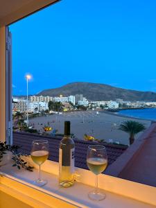 dos copas de vino blanco sentadas en una cornisa con una ventana en Apartamento El Faro del Cabezo, en Arona
