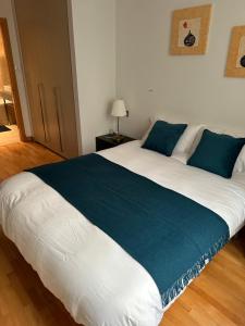 uma grande cama branca com almofadas azuis num quarto em Britain in the Sun at Luxurious Ocean Village em Gibraltar