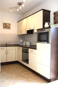 a kitchen with white cabinets and a refrigerator at Ferienhaus Lütt Eiland in Polchow