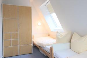 Dormitorio pequeño en el ático con cama y ventana en Hafenhäuser Breege - Ferienwohnung 9 Strandläufer, en Breege