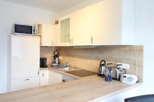 a kitchen with white cabinets and a sink at Kurparkcarree - Ferienwohnung Meeresbrise in Juliusruh
