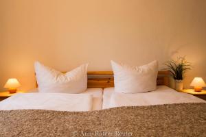 two beds with white sheets and pillows in a room at Ferienhaus am Ufer - Ferienwohnung Strandsand in Sassnitz