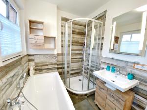 a bathroom with a tub and a shower and a sink at Doppelhaushälfte Freyh 1 am Golfplatz in Ranzow +13 photos