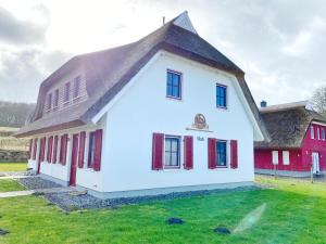 une maison blanche avec un toit marron et des fenêtres rouges dans l'établissement Doppelhaushälfte Freyh 1 am Golfplatz, à Ranzow