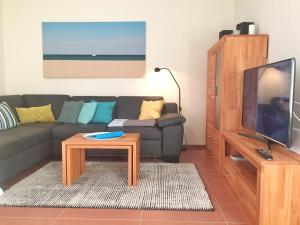 un soggiorno con divano, TV e tavolo di Kurparkcarree - Ferienwohnung "Amber" a Juliusruh