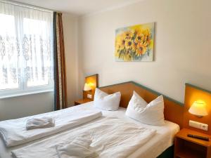 a bedroom with a bed with white sheets and a window at Ferienwohnung 10 "Bootsmann Hannes" in Wiek auf Rügen