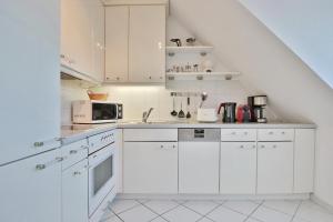 een witte keuken met witte kasten en een magnetron bij Haus Kurparkblick Haus Kurparkblick Appartement 11 in Timmendorfer Strand