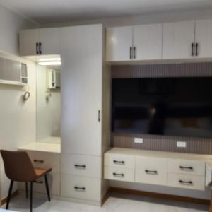 a kitchen with white cabinets and a flat screen tv at Twin Hearts 328 in Roxas City