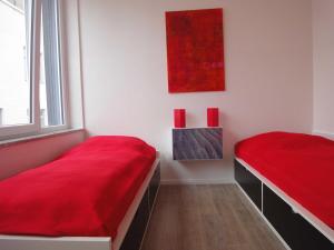 ティメンドルファー・シュトラントにある_KUR8_ _ Ferienwohnung Strandlaeufのベッドルーム1室(赤いシーツと窓付)
