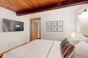 a bedroom with a white bed and a flat screen tv at Creekside Cabin in Rhododendron +13 photos