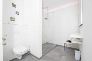 La salle de bains blanche est pourvue de toilettes et d'un lavabo. dans l'établissement _ERL43_ PIER 43, à Niendorf