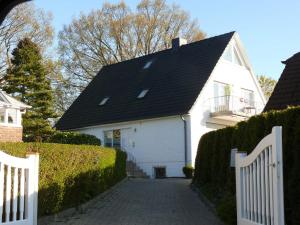 ein weißes Haus mit einem schwarzen Dach und einer Auffahrt in der Unterkunft (WIK7a) in Niendorf