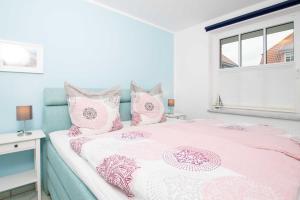 Un dormitorio con una cama rosa y blanca y una ventana en OST5a, en Niendorf