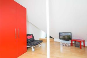 um armário vermelho num quarto com uma cadeira e uma televisão em _OST6_ _ Ferienwohnung Treibholz em Niendorf