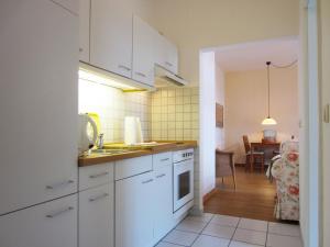 a kitchen with white cabinets and a dining room at Ferienwohnung Am Molli Nr. 4 in Kühlungsborn