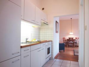 eine Küche mit weißen Schränken und ein Esszimmer in der Unterkunft Ferienwohnung Am Molli Nr. 2 in Kühlungsborn