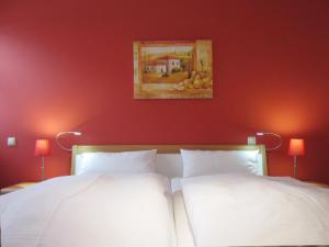 - 2 lits dans une chambre dotée d'un mur rouge dans l'établissement Ferienwohnung Ostseeblick, à Kühlungsborn
