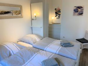 Bett in einem Zimmer mit weißer Bettwäsche und Handtüchern in der Unterkunft Ferienwohnung "Aloki" in Sankt Peter-Ording