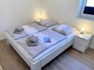 een wit bed met 2 kussens en 2 tafels bij Ferienwohnung "Strandläufer 1" in Sankt Peter-Ording