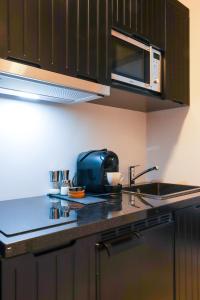 a kitchen with a sink and a microwave at Moderne Ferienwohnung mit Sonnenterrasse & Gartenblick - Strandnah und Parkplatz in ruhiger Lage - hoher Schlafkomfort in Scharbeutz