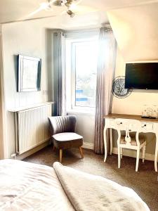 a bedroom with a bed and a desk and a window at Highfield Guesthouse in Skipton