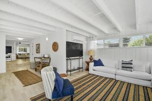 ein Wohnzimmer mit einem weißen Sofa und einem TV in der Unterkunft Santorini Pool House Wilton Manors Walk to the Dr in Fort Lauderdale