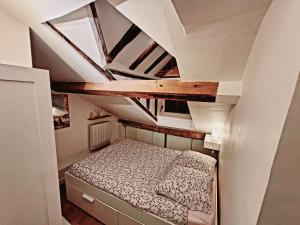 ein kleines Schlafzimmer mit einem Bett im Dachgeschoss in der Unterkunft Le Cosy Macaron - Au cœur de Versailles in Versailles