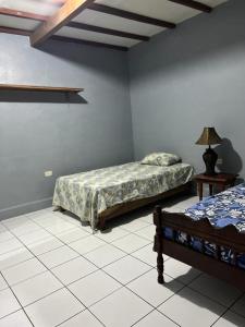 um quarto com 2 camas e um candeeiro num piso de azulejo em Hotel Pacific Surf Tunco Beach with AC best room Surf City em Tamanique