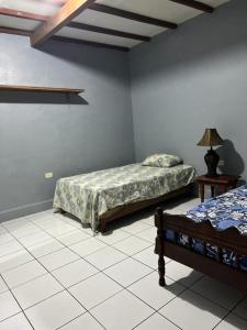 a bedroom with two beds and a lamp on a tiled floor at Hotel Pacific Surf Tunco Beach with AC best room Surf City in Tamanique