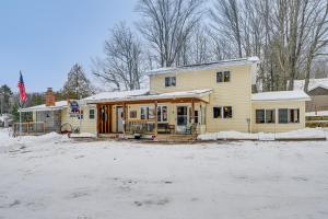 a yellow house with snow on the ground at Lakefront Suring Home with Pool Table and Views! in Mountain